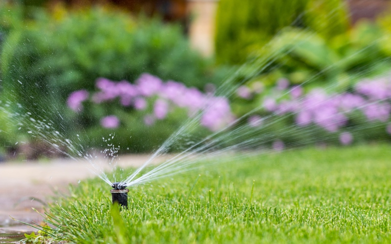 Sprinklers water a beautiful green lawn, thanks to professional sprinkler services in Utah provided by Hot Shot Sprinkler Repair & Landscape.