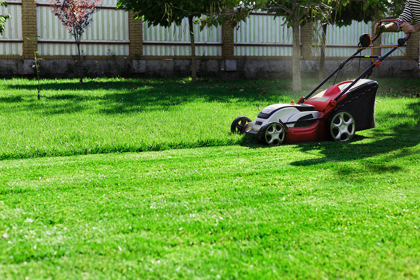 A person mowing a lawn - Hot Shot offers fertilization and yard cutting services in Farmington, UT to keep your yard beautiful year-round.