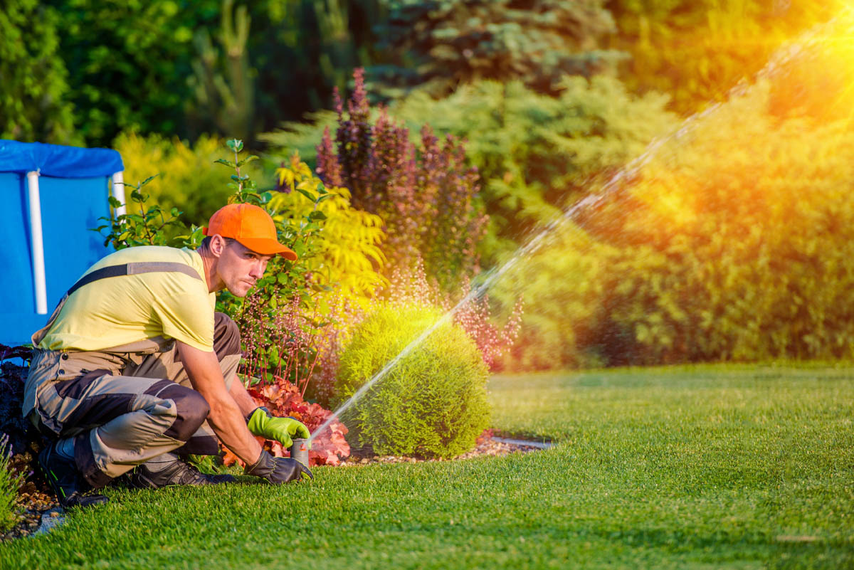 A professional from Hot Shot Sprinkler Repair & Landscape fixing clogged nozzles and other issues with sprinklers.